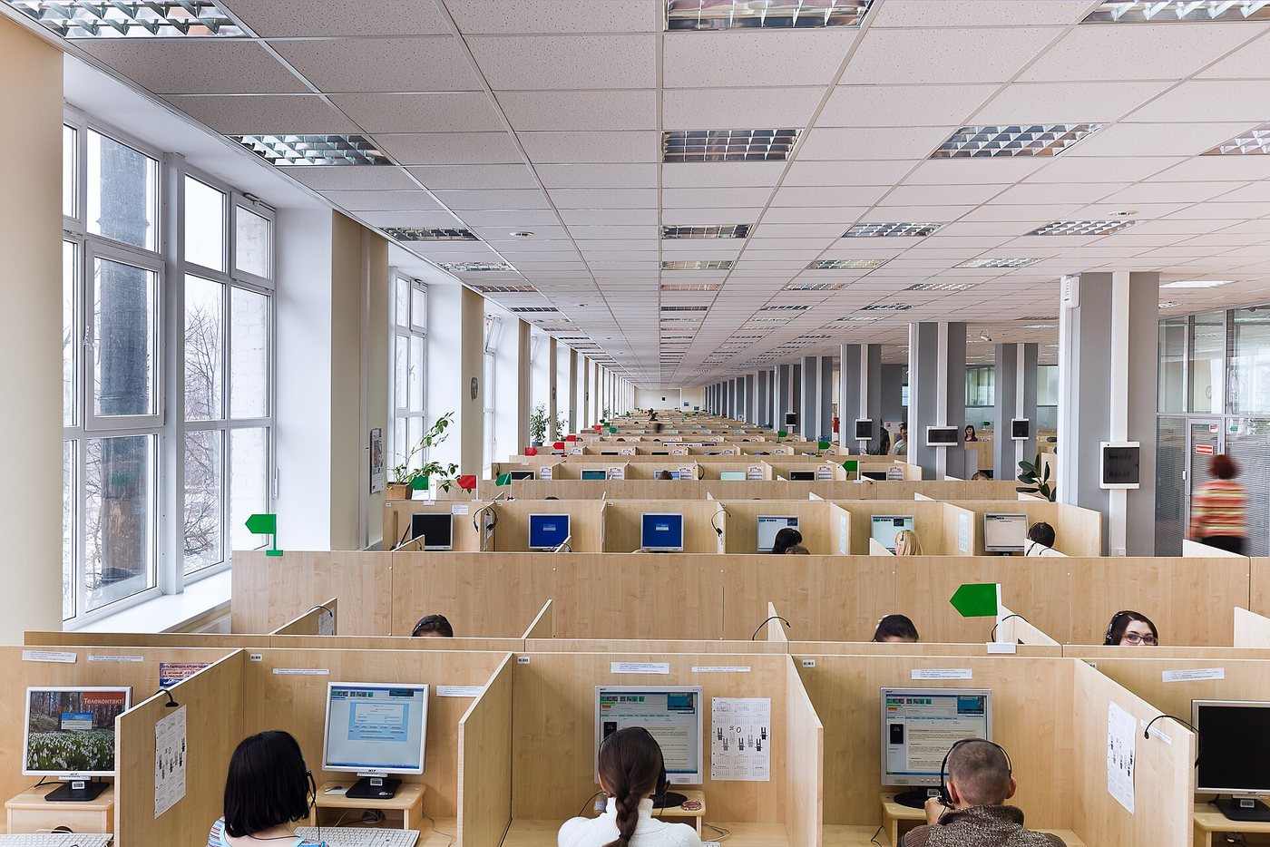 A large, bright open-plan call centre in Oryol, Russia, with agents wearing headsets working at rows of partitioned desks.