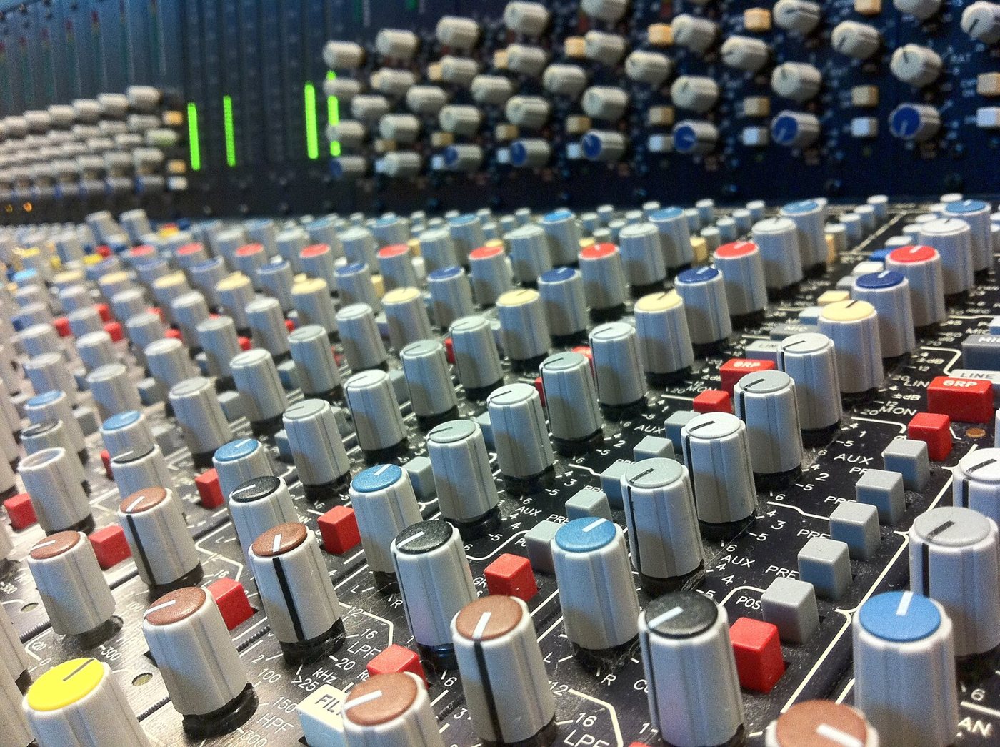 Rows of colour-capped rotary knobs and buttons on an analogue mixing console in a music production studio in Cologne, Germany.