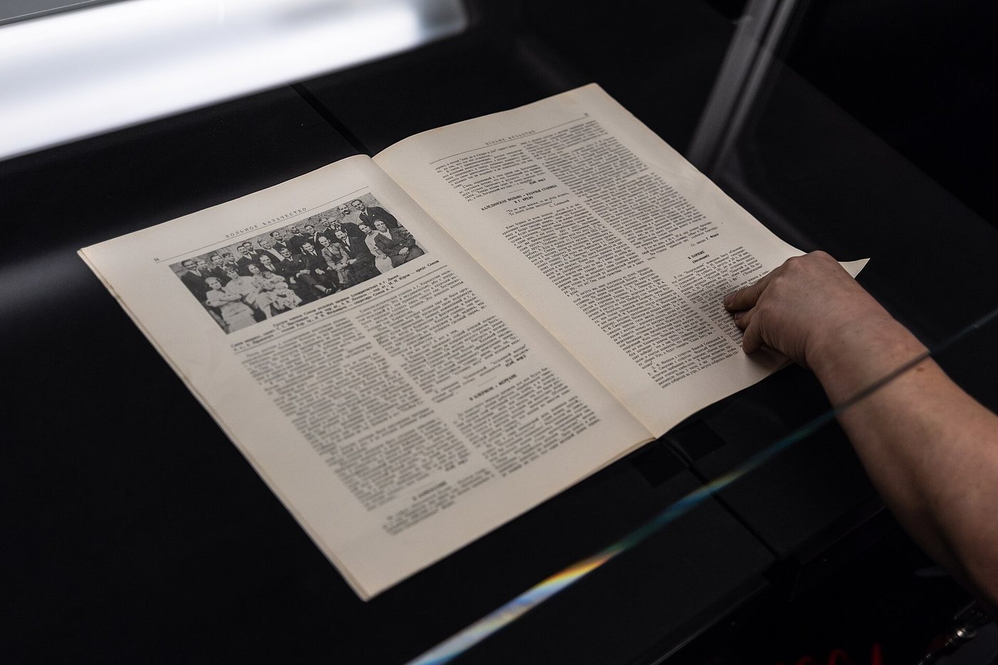 A hand holds open a printed book on a manual book scanner during digitisation at the National Library of the Czech Republic.