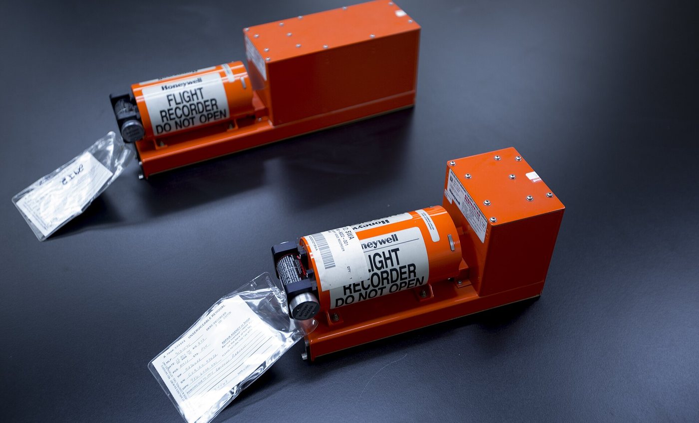 The orange cockpit voice recorder and flight data recorder from Southwest Airlines flight 4013, photographed by the NTSB on a dark background.